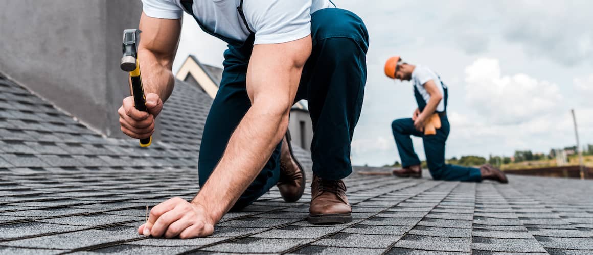 Two men fixing roof.