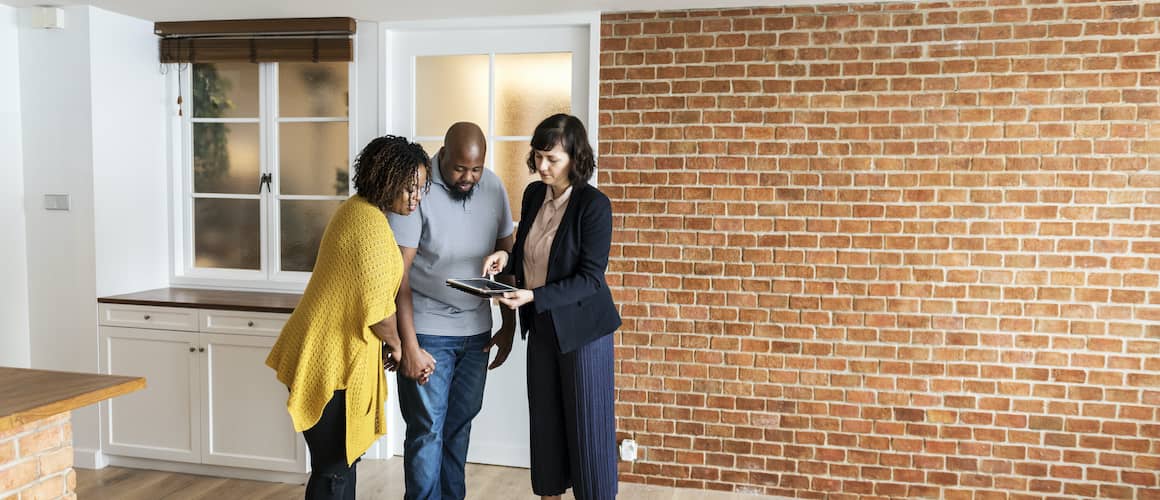 Couple exploring a new home with a realtor, examining or considering a property.