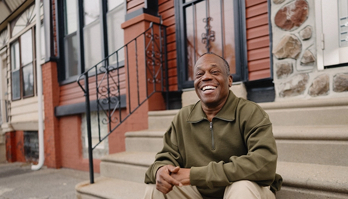 Man sitting on front steps smiling.