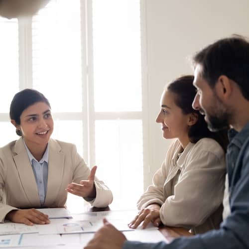 Three individuals in discussion around a table. 