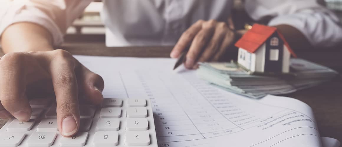 A man working on calculations with a calculator, possibly related to finances or budgeting.