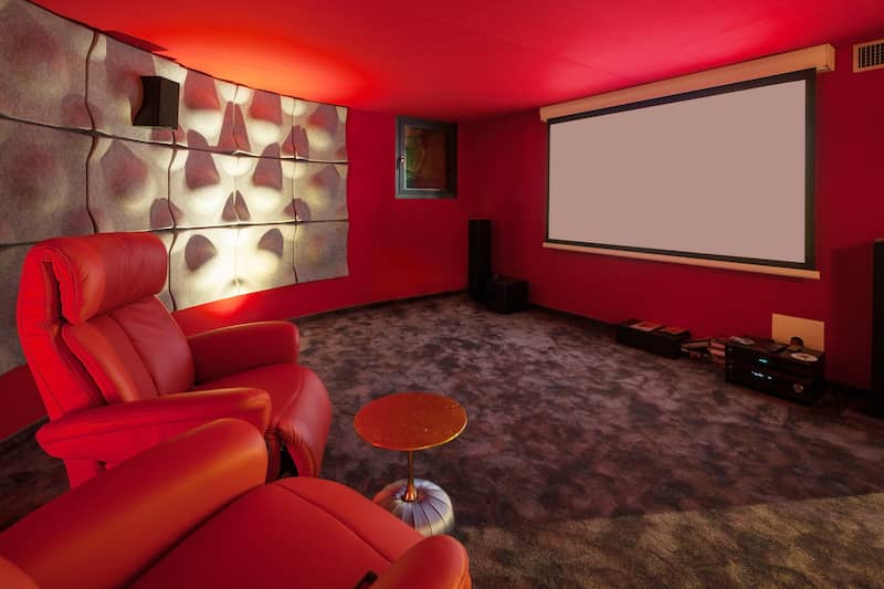 RHB Assets From IGX: A luxurious home theater with bold colors, unique seating, and a large projector screen.