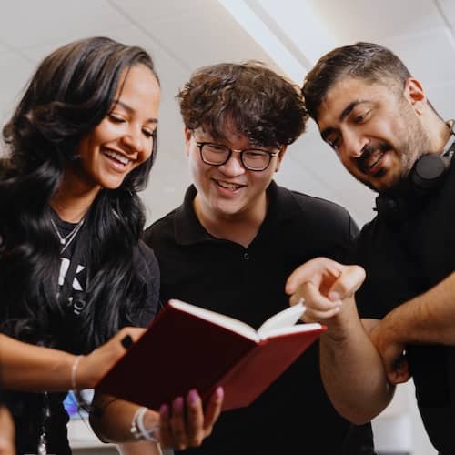 Three team members reviewing notes in a notebook.