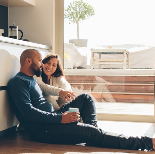 Couple on floor relaxing in kitchen.