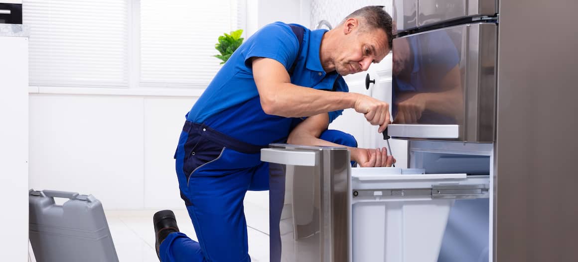 An appliance repairman at work, possibly in a residential setting.