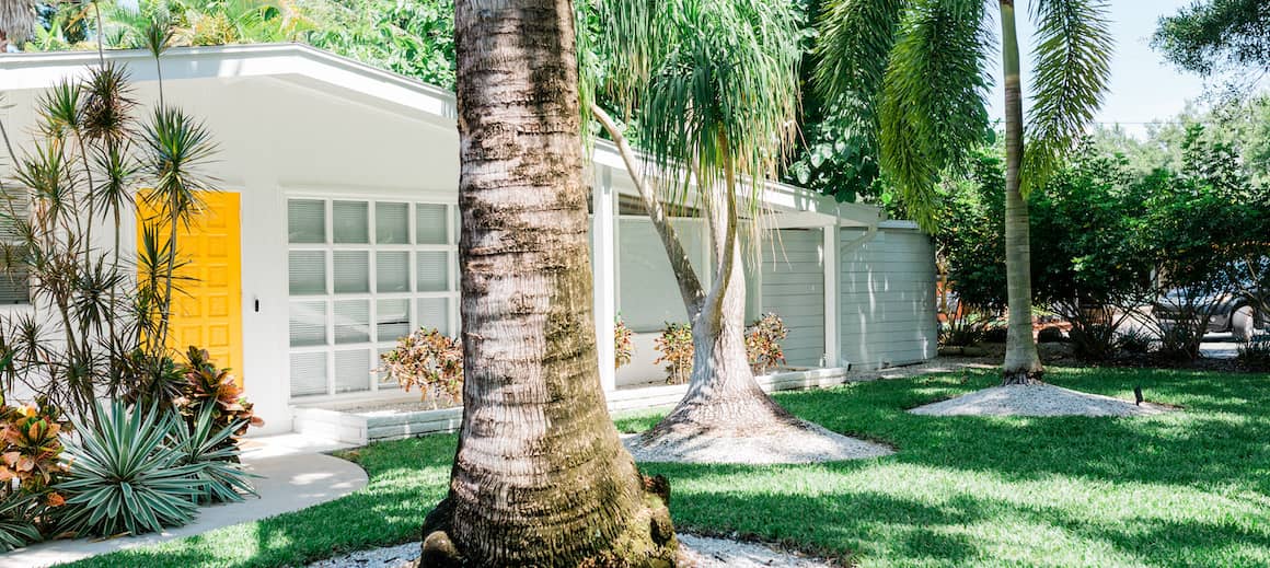 Beach home with palm trees in front.