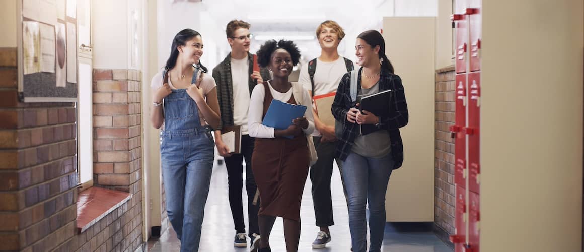 A group of five students walking together in a school hallway.