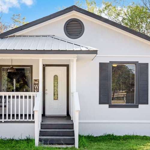 A small white one-story house with a neatly maintained front yard, depicting a cozy residential setting.