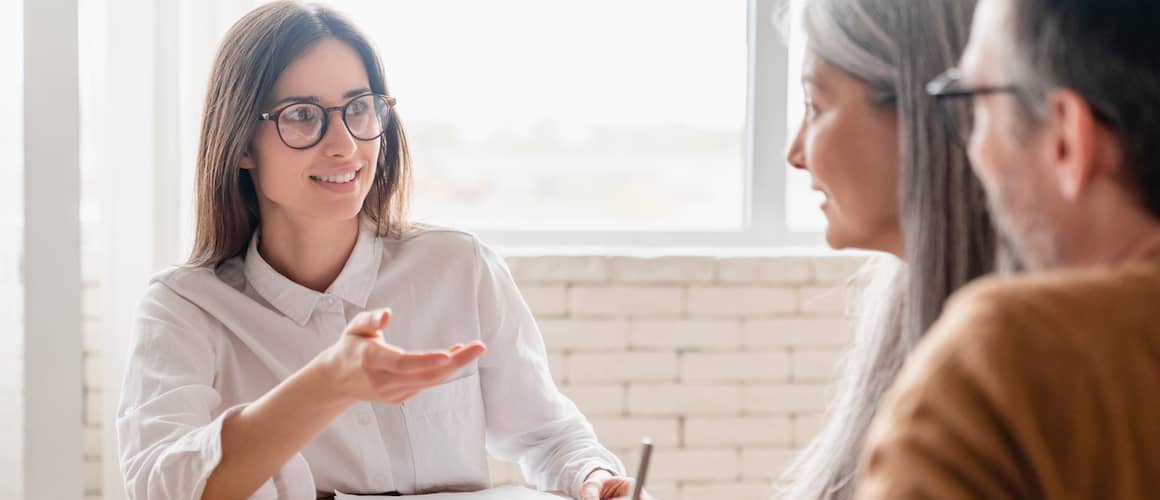 Financial advisor speaking to elderly couple in office.