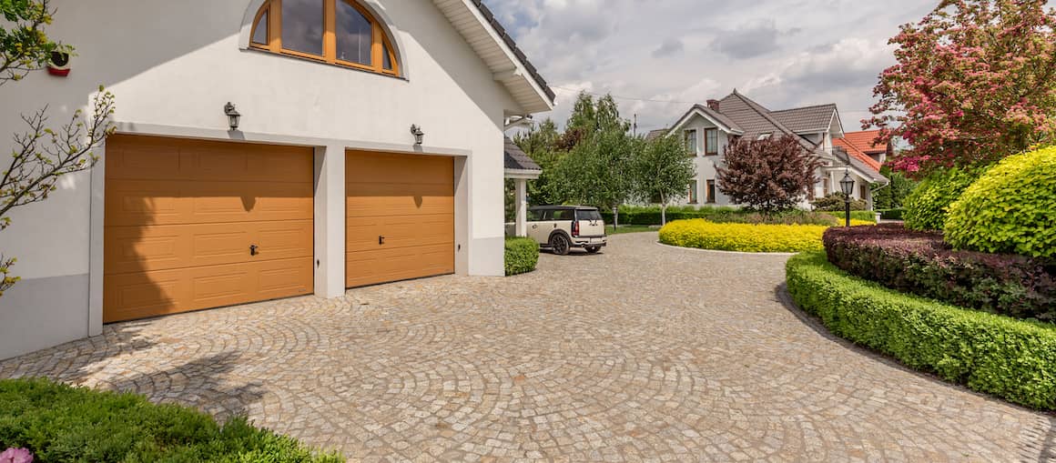 RHB Assets From IGX: A brick and stone driveway with double garage doors.