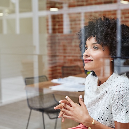 Young woman at work looking out window.