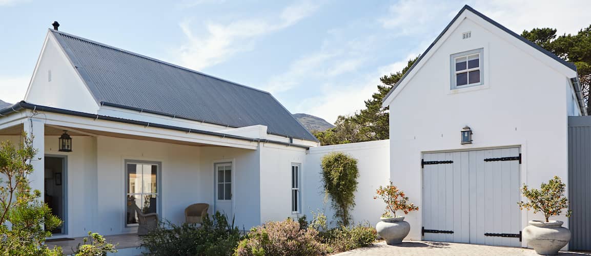 Exterior of white two-story countryside house with black shutters and roof.