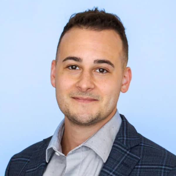 Headshot of a man smiling against a blue background.