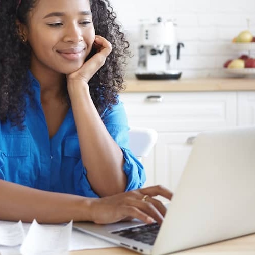 Young woman smiling and using a laptop.
