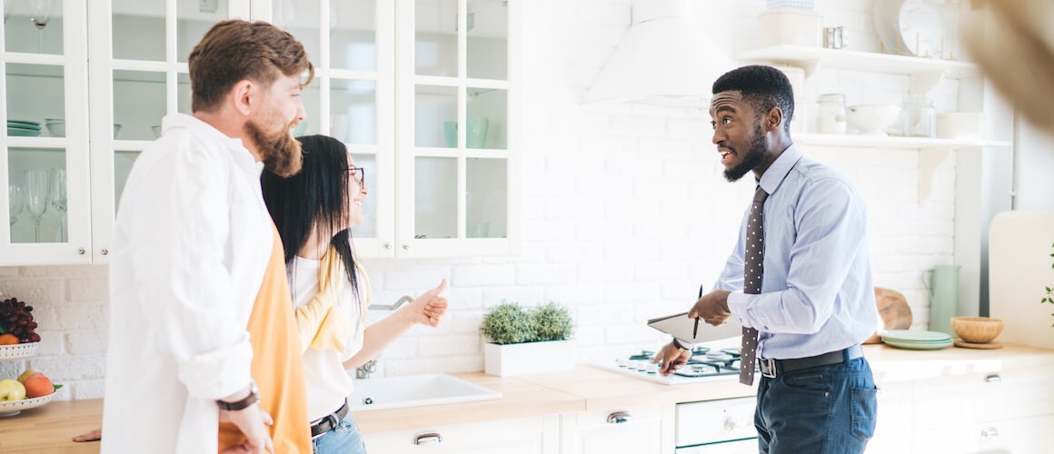 A couple with a realtor examining a new kitchen space in a property.