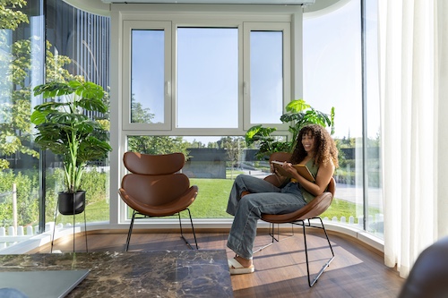 Young woman sitting in sunroom reviewing notebook and smiling.