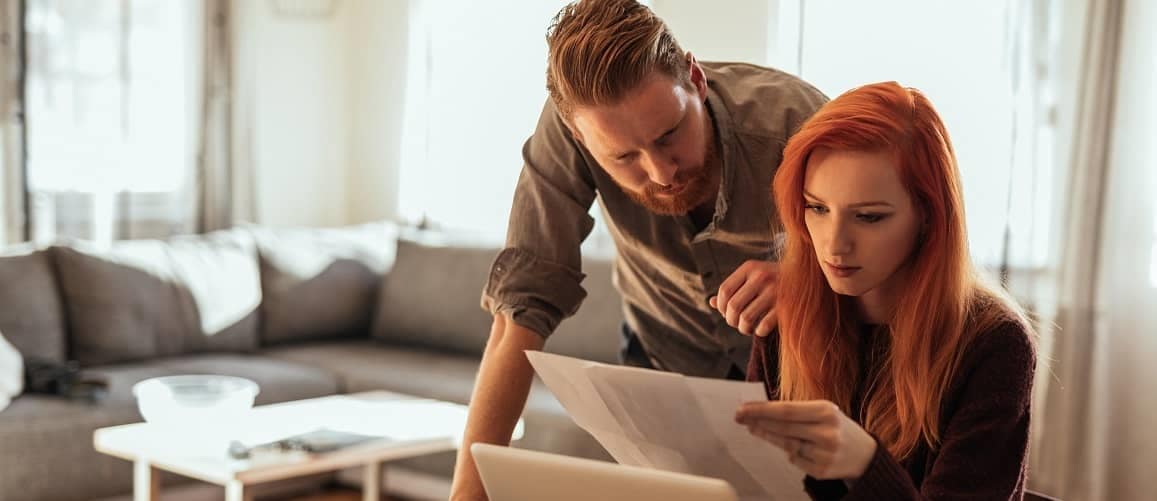 A young couple reviewing paperwork together, possibly related to a mortgage or property.