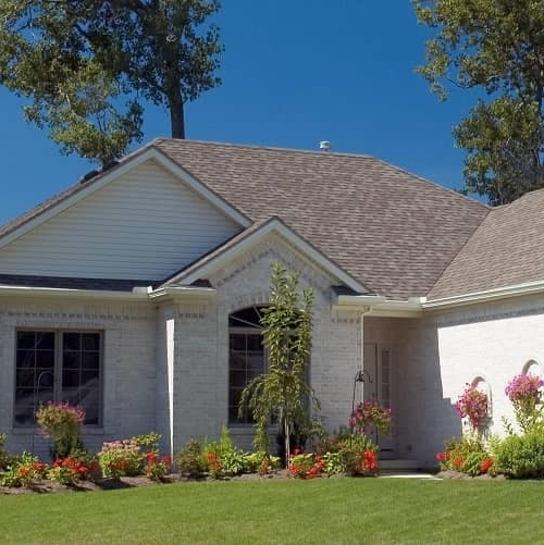 A white house nestled among trees in a suburban area.