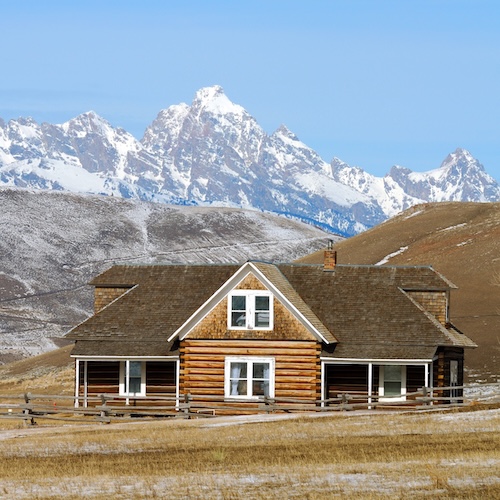 House in Wyoming with a large yard against backdrop of the mountains.