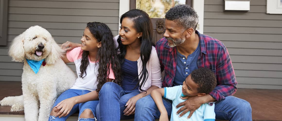 A family sitting on the porch with their pet having enjoyable moment.