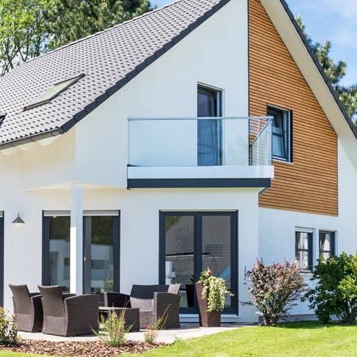 A contemporary house with a spacious yard and a balcony, showcasing modern architecture.