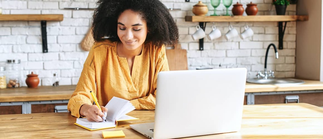 Woman writing and on laptop.