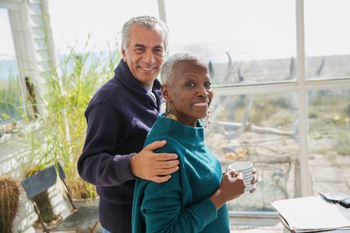 Senior couple having coffee in screened in porch at beachhouse.