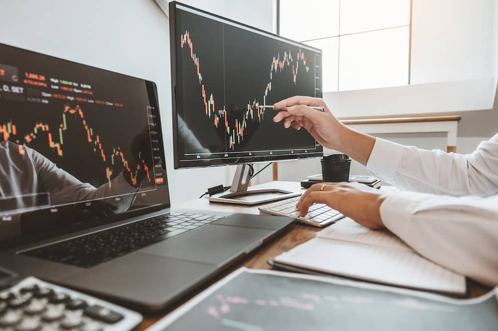 Person in front of computer monitors tracking stock charts.