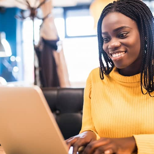 African American woman with laptop and phone in a cafe