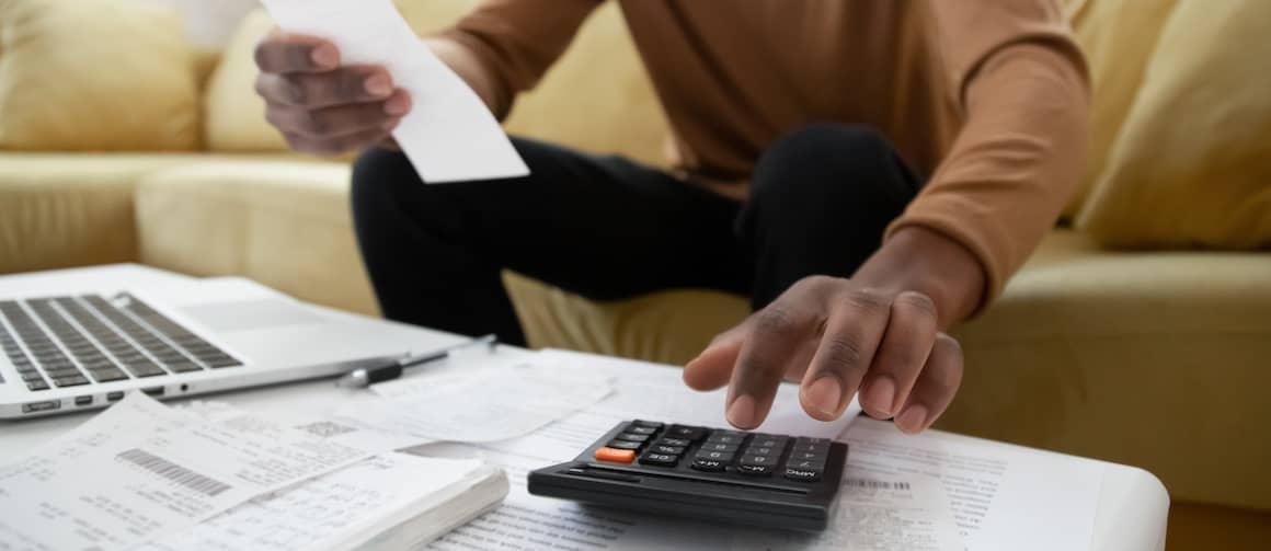 Man sitting on couch calculating income.