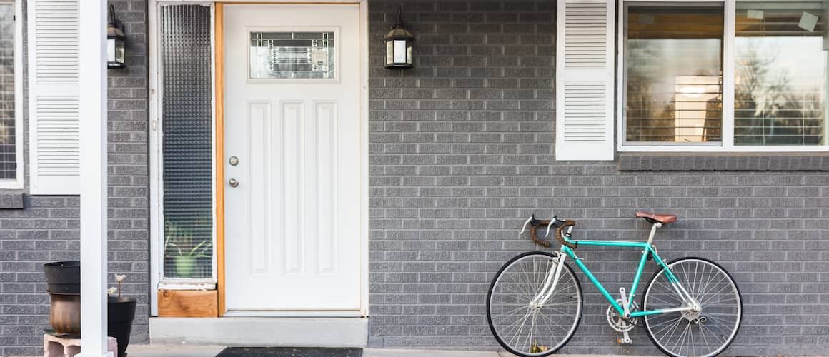 A turquoise bicycle on a front porch, adding a decorative element to the entrance of a home.