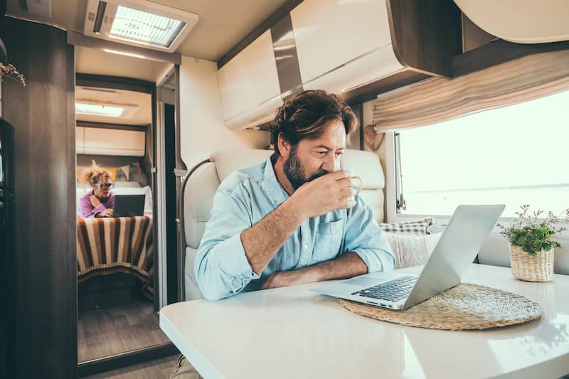 Modern man and woman work together on laptop in alternative office motor home.