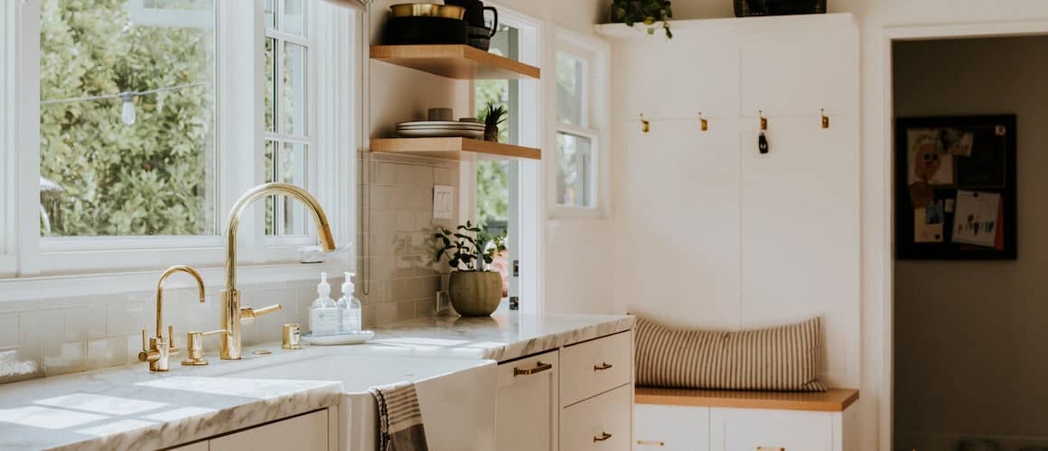 Beautiful remodeled small kitchen with open floating shelves, white marble with gold finishes.