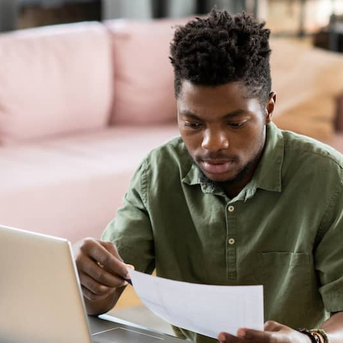 A focused image of a man engrossed in working with paperwork, indicating involvement in real estate transactions, financial planning, or administrative tasks related to home buying or mortgage processes.