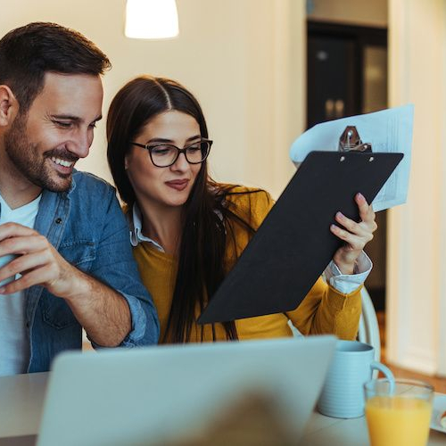 Couple going through a list, potentially related to a property checklist or planning details.