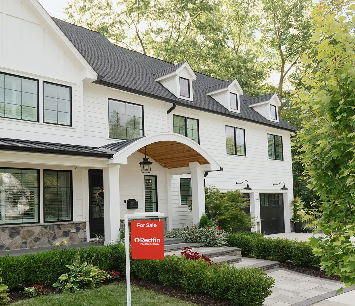 A large white house with a Redfin for sale sign in the front yard.