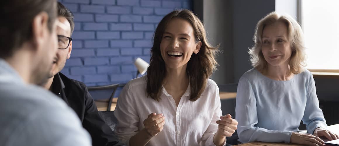 Woman laughing during relaxed work meeting.