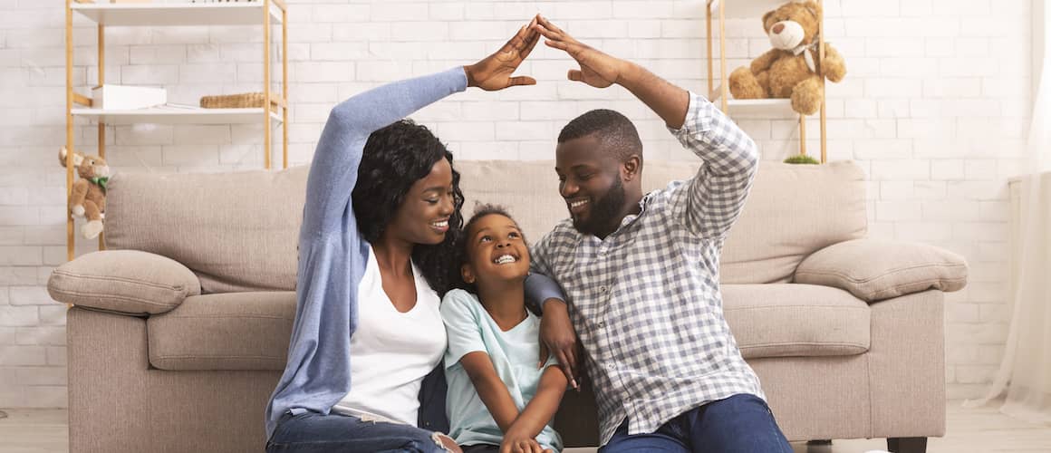 A young family creating a symbolic roof over their daughter's head, possibly representing homeownership aspirations or planning.