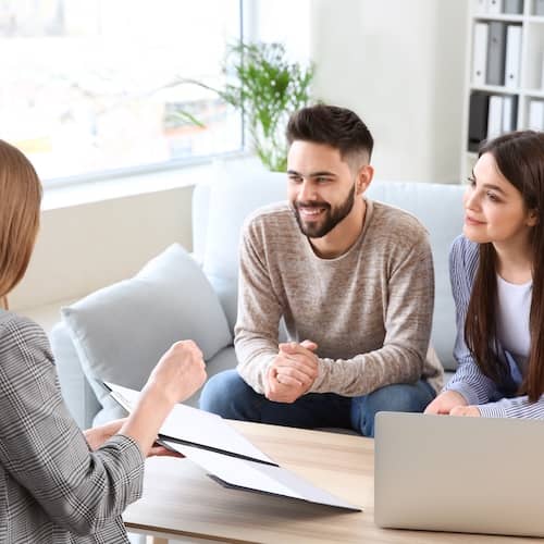 Young couple reviewing documents with a real estate agent.