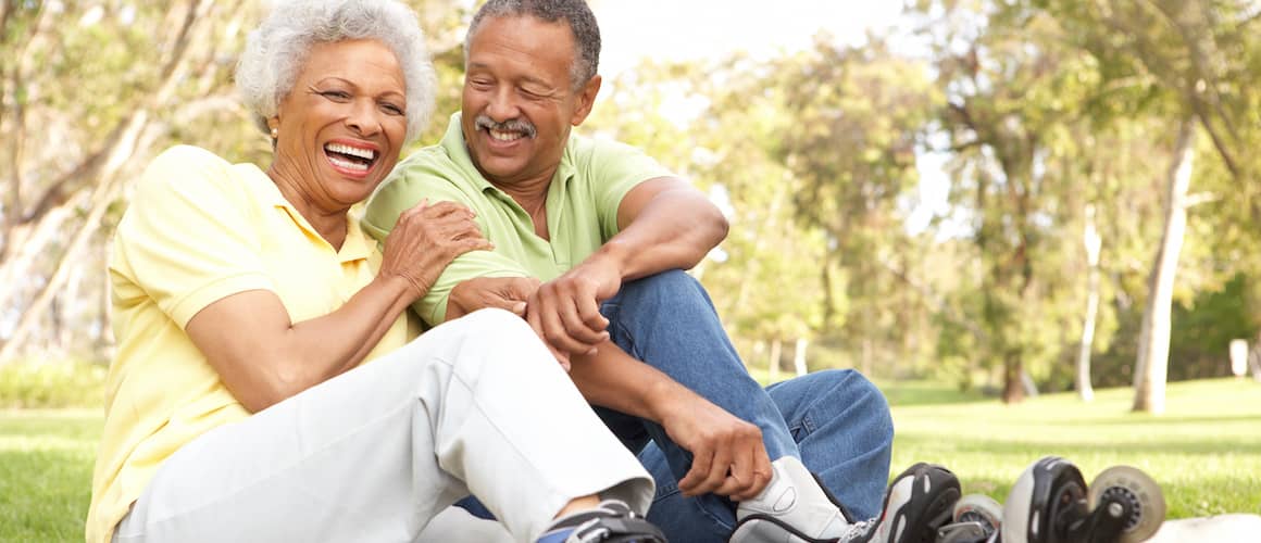 African American senior couple at a park wearing inline skates.