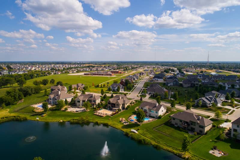 RHB Assets From IGX: Aerial view of a residential rural neighborhood in Iowa with green lawns.