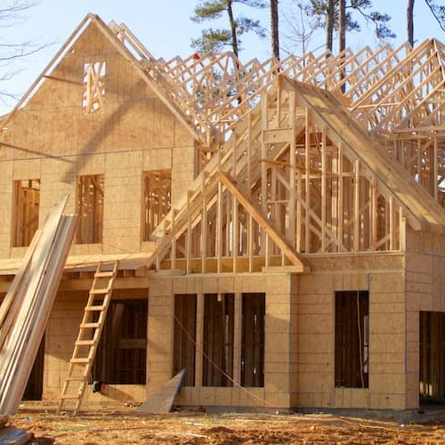 A house under construction, showcasing the building process with construction materials and equipment.