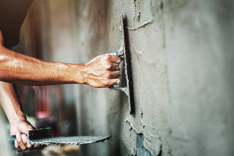 Close up of worker applying plaster to wall in a house.