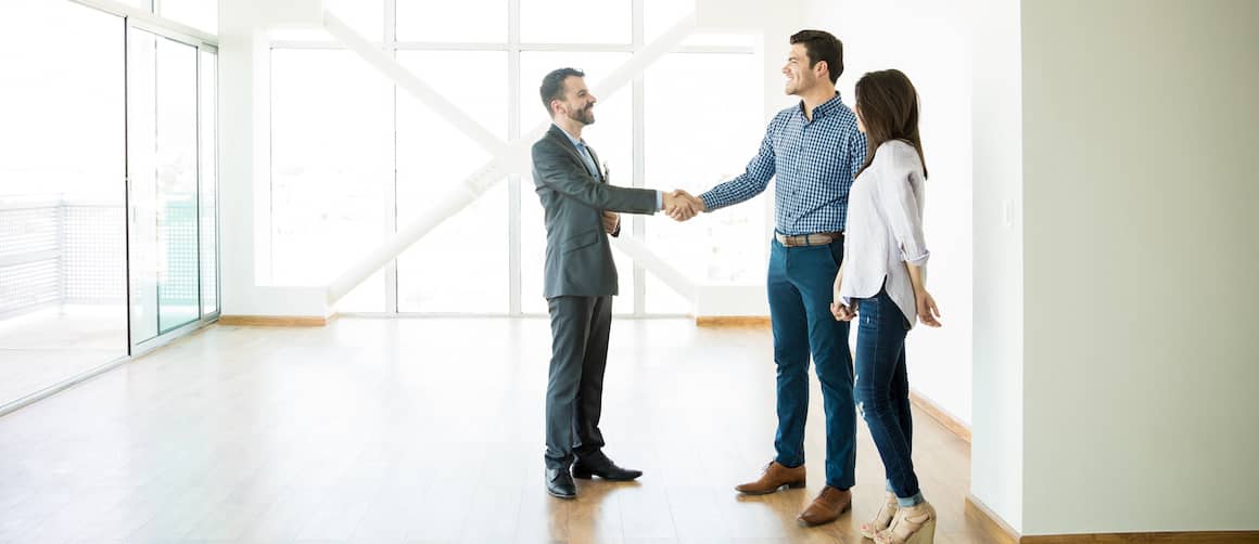 RHB Assets From IGX: Happy couple shaking hands with a realtor in front of their new home.