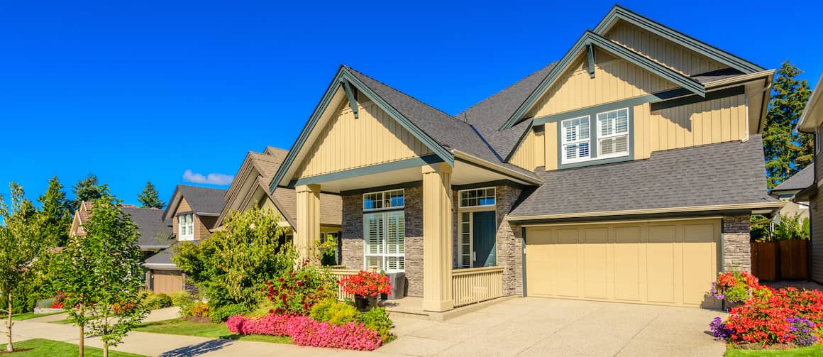 Large yellow house with colorful front gardens.