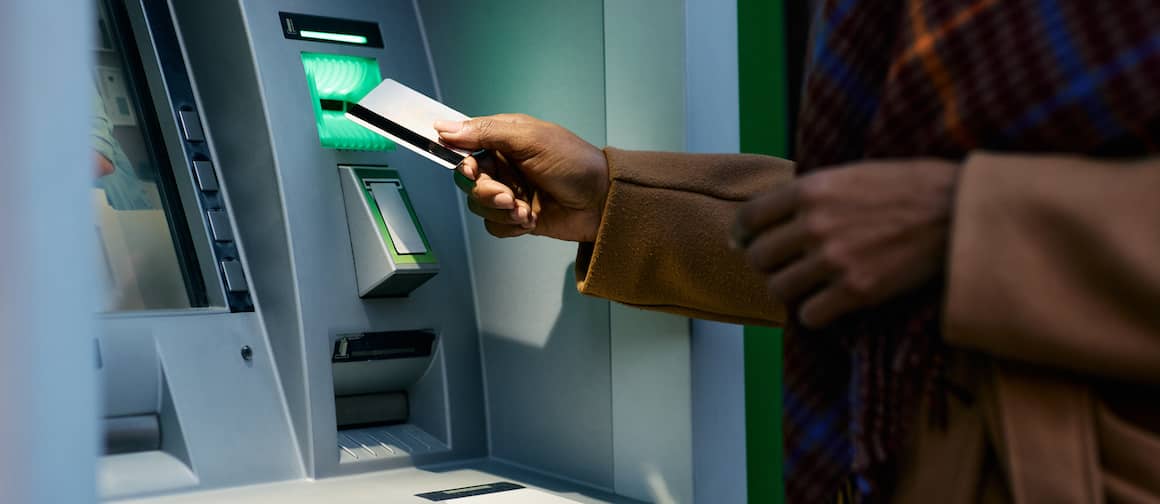 Closeup of woman's hands as she uses an ATM.