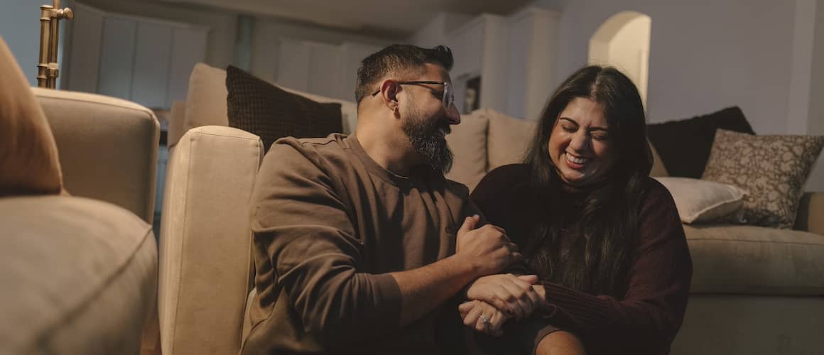 Couple laughing in living room together.