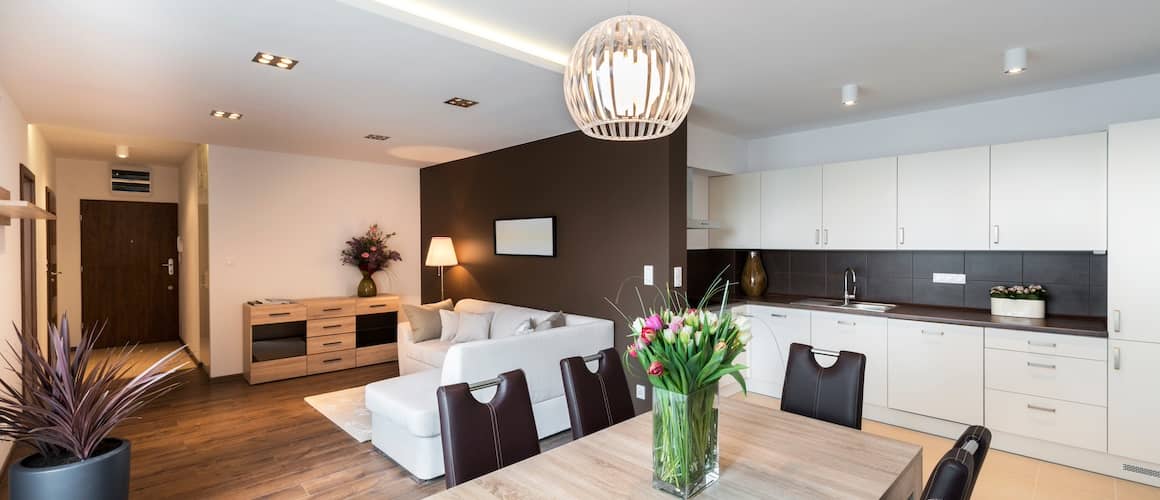 A furnished luxury apartment showing an open concept plan with the kitchen, dining and living areas all visible.