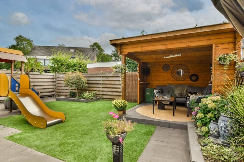 Neat patio with several activity zones, including a sitting area with playground and small garden near wooden fence