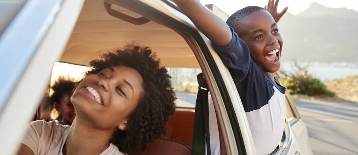 Mother pretending to drive car while son yells out window.